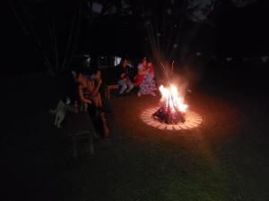 a group of people sitting around a fire in the dark at Sítio Pand'Oro in Atibaia