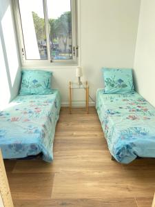 two beds in a room with two windows at Marina appartement sur l’eau in Le Grau-du-Roi