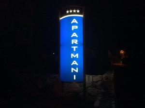a blue sign for a hotel in the dark at Apartments Kovacic in Malinska