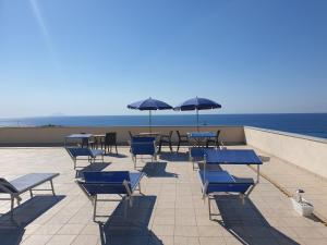 a patio with blue chairs and tables and umbrellas at Eolie House in Tropea