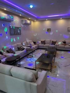 a living room with couches and tables and purple lights at شاليه دانة الرس in Ar Rass