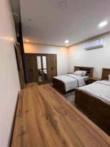 2 łóżka w pokoju z drewnianą podłogą w obiekcie شاليه دانة الرس w mieście Ar-Rass