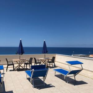 un grupo de sillas y mesas con el océano en el fondo en ele&gio accomodation en Tropea