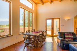 ein Esszimmer mit einem Tisch, Stühlen und Fenstern in der Unterkunft Southwest Stunner in Ranchos de Taos