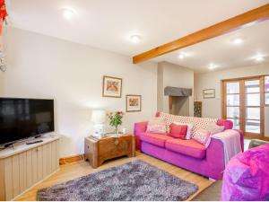 a living room with a pink couch and a tv at 40 New Row in Pwllheli