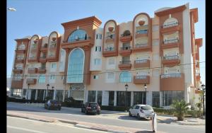 a large building with cars parked in front of it at Résidence les Dunes- S+3 -Chott Meriem Kantaoui Sousse in Chott Meriem