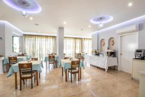a dining room with tables and chairs and a kitchen at Panorama Hotel in Karpathos