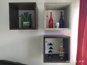 two shelves with glass vases on a wall at APARTAMENTO 2 QUARTOS MOBILIADO - GARANHUNS - PE in Garanhuns