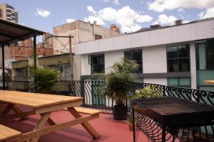 a patio with a wooden table and bench on a balcony at La Familia Hostel - Parque Poblado in Medellín