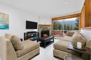 a living room with a couch and a fireplace at Ski In Ski Out 3BR Townhome in Creekside by Harmony Whistler in Whistler