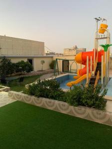 a playground with a slide in a yard with green grass at شاليهات تركواز in Ash Shuwaybiţ