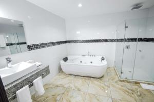 ein Bad mit einer Badewanne, einem Waschbecken und einer Dusche in der Unterkunft Basha Hotel & Restaurant in San Pedro Sula