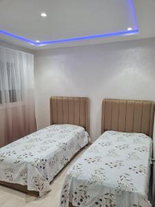 two beds in a bedroom with a blue light at Appartement a Nador in Nador