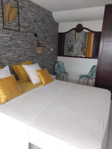 ein Schlafzimmer mit einem großen weißen Bett mit gelben Kissen in der Unterkunft STUDIO Feuilles d'or in La Trinité