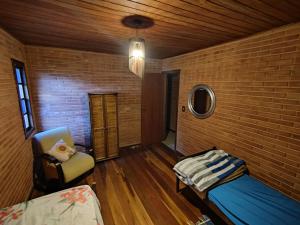 a room with a brick wall and a bed and a chair at toda paz do universo in Nova Friburgo