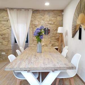 a dining room with a wooden table and white chairs at Casa Elvira, terraza con fabulosas vistas in Pontevedra