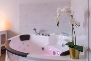 eine weiße Badewanne mit einer Vase mit Blumen darin in der Unterkunft LOC TROTTEUR LE CACAO - Balnéo, Gare Lourdes in Lourdes + 30 Fotos