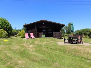 a cabin with pink chairs and a table in the grass at Cedar Lodge in Bodmin