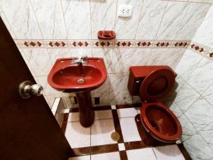 uma casa de banho com um lavatório vermelho e um WC. em Hostal Muchik em Chiclayo