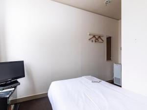 um quarto com uma cama e uma televisão de ecrã plano em Tabist Business Hotel Suehiro Matsuyama em Matsuyama