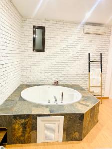 eine große Badewanne in einem Zimmer mit Ziegelwand in der Unterkunft SUITE SORPRESA VuT LA TABERNA in Arenas de San Pedro