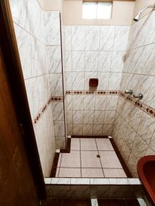 y baño con ducha y suelo de baldosa. en Hostal Muchik, en Chiclayo