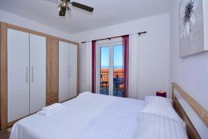 a white bedroom with a bed and a window at Apartment 'MIMO' in Milna - Hvar in Milna