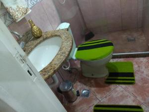 ein Bad mit einem grünen und weißen WC und einem Waschbecken in der Unterkunft STUDIO Centro Lacerda in Campos dos Goytacazes