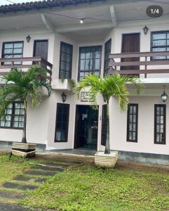 two palm trees in front of a building at Pousada da Jaqueira - EPP in Rio das Ostras