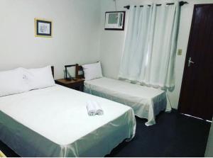a room with two beds and a window at Pousada da Jaqueira - EPP in Rio das Ostras