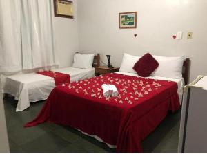 a hotel room with two beds with red sheets at Pousada da Jaqueira - EPP in Rio das Ostras