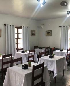 a dining room with tables and chairs with white table cloth at Pousada da Jaqueira - EPP in Rio das Ostras