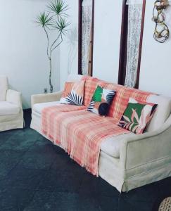 a living room with a white couch with pillows at Pousada da Jaqueira - EPP in Rio das Ostras