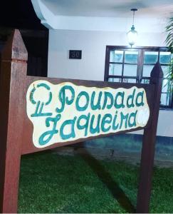 a wooden bench with a sign on it in a yard at Pousada da Jaqueira - EPP in Rio das Ostras