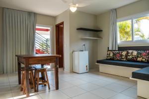 a living room with a table and a refrigerator at Pousada Dormida do Peixe in Praia do Rosa