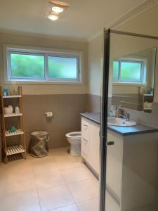 a bathroom with a sink and a toilet and two windows at Contemporary On Cuttriss Inlet Side in Inverloch