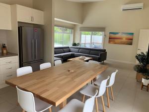 a kitchen and dining room with a wooden table and white chairs at Contemporary On Cuttriss Inlet Side in Inverloch