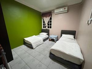 2 camas en una habitación con una pared verde en Hanif Homestay, en Kuching