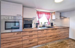 a kitchen with wooden cabinets and a sink and a microwave at Nice Home In Nova Diklenica With Sauna in Nova Diklenica