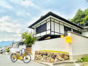 a yellow bike parked in front of a house at Miyajima Guest House Mikuniya in Miyajima