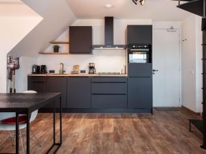 a kitchen with black cabinets and a table at Apartment Sneekermeer with Water Sports Access in Offingawier +32 photos