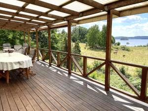 eine Holzterrasse mit einem Tisch und Blick auf ein Feld in der Unterkunft Holiday home RIMFORSA V in Rimforsa