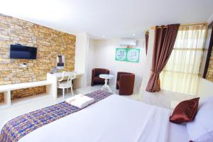 1 dormitorio con cama blanca y pared de ladrillo en The Djakarta Anandita Syariah Hotel, en Samarinda