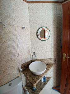 W łazience znajduje się umywalka, toaleta i lustro. w obiekcie Flat do Léo w mieście Praia de Araçatiba