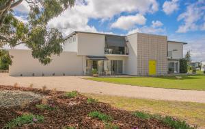 une maison blanche avec une porte jaune dans l'établissement 'Ooh La La' is a quirky French inspired apartment, à Goolwa South