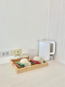 a tray with cups and a coffee maker on a counter at โรงแรมเอสซีเรสซิเดนซ์ มุกดาหาร in Mukdahan