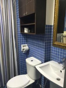 Baño de azulejos azules con aseo y lavamanos en Amisha Home Design & Comfortable 2 Bedrooms Apartment en Petaling Jaya