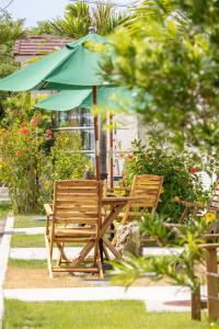 two wooden chairs and a table with an umbrella at Hotel Santa Barbara Miyakojima Resort in Miyako-jima