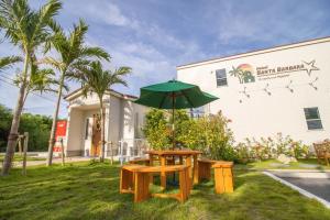 a picnic table with an umbrella in front of a building at Hotel Santa Barbara Miyakojima Resort in Miyako-jima