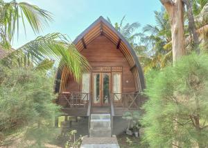 a small wooden house in the middle of trees at Nusa Indah Bungalows in Gili Air